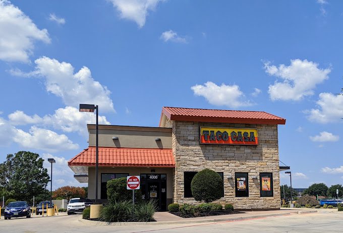 A taco bell restaurant with cars parked in front of it.