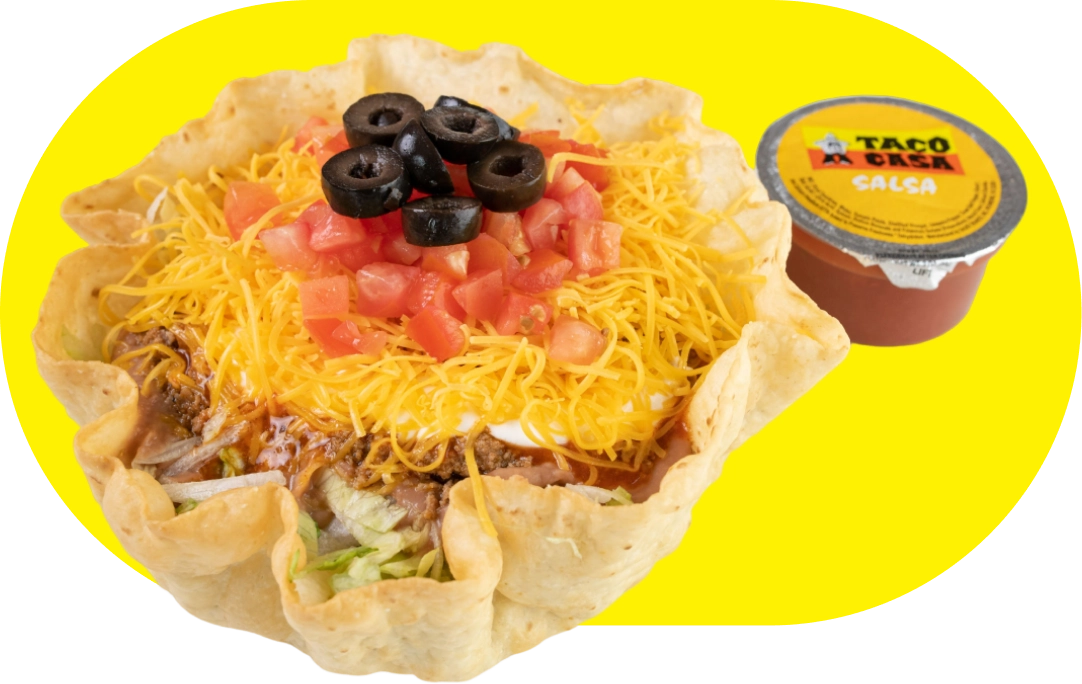 A taco salad with cheese, olives and tomatoes.