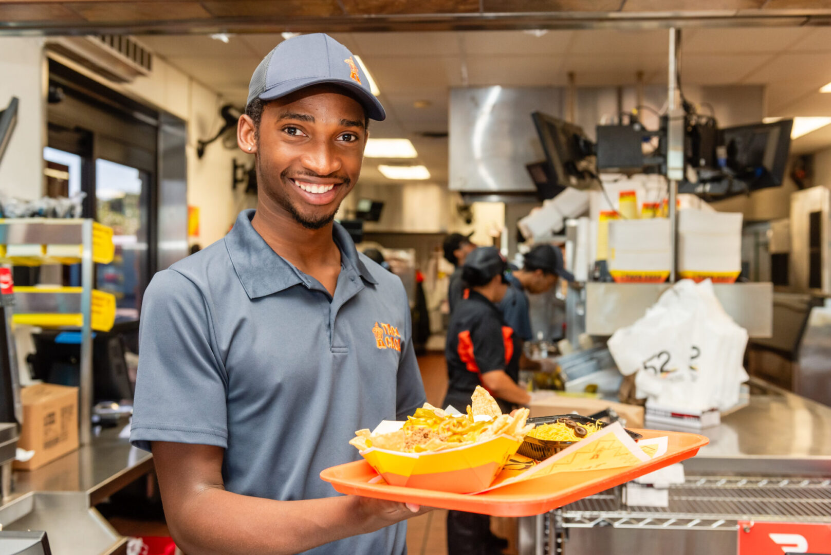 A man holding a tray of food in a kitchen.